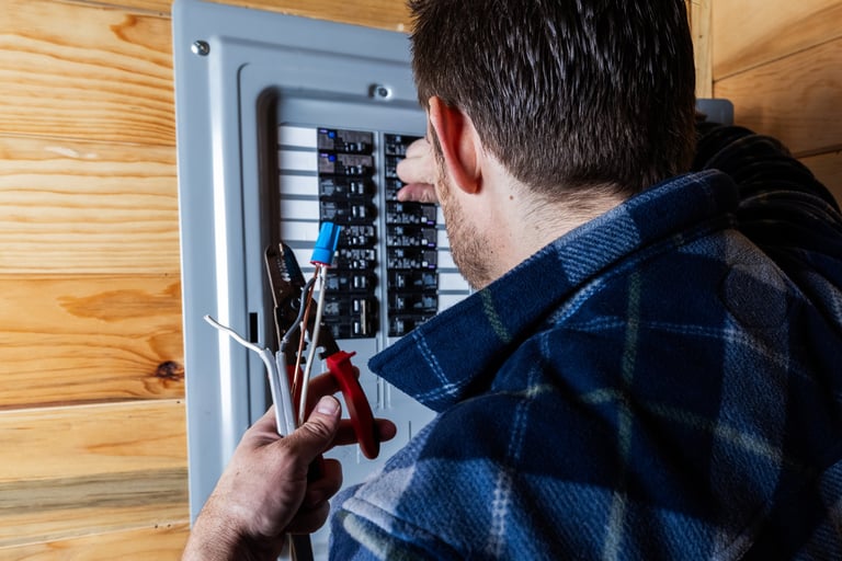 Residential electrician preparing cables for installation in a circuit breaker box